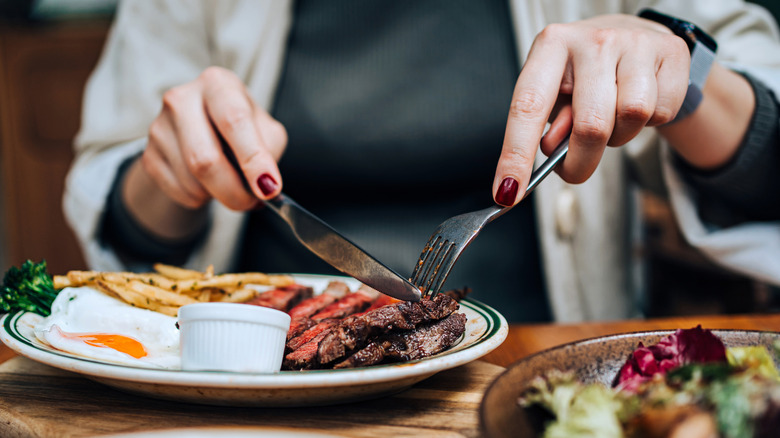 A person cutting into a steak at a restaurant