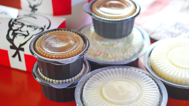 KFC meal stacked on table in plastic containers and cardboard boxes