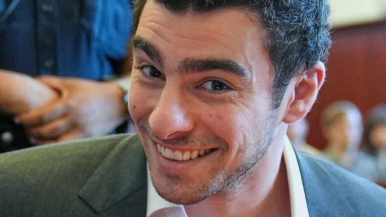 Closeup of Luigi Mangione smiling in court