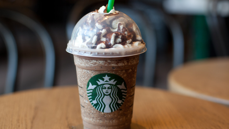 A Starbucks Frappuccino with whipped cream in a plastic cup