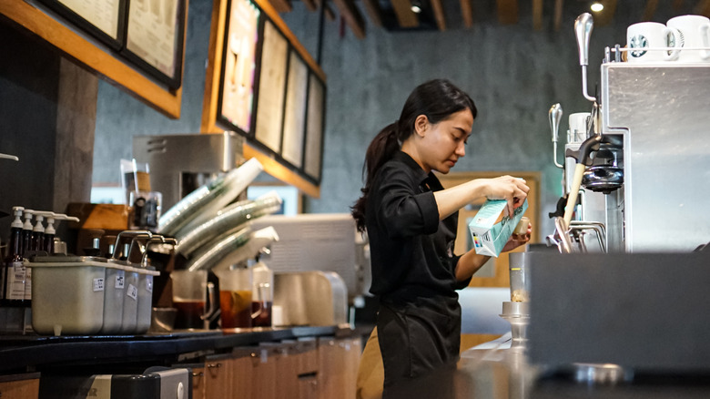 A Starbucks barista prepares a drink for a customer