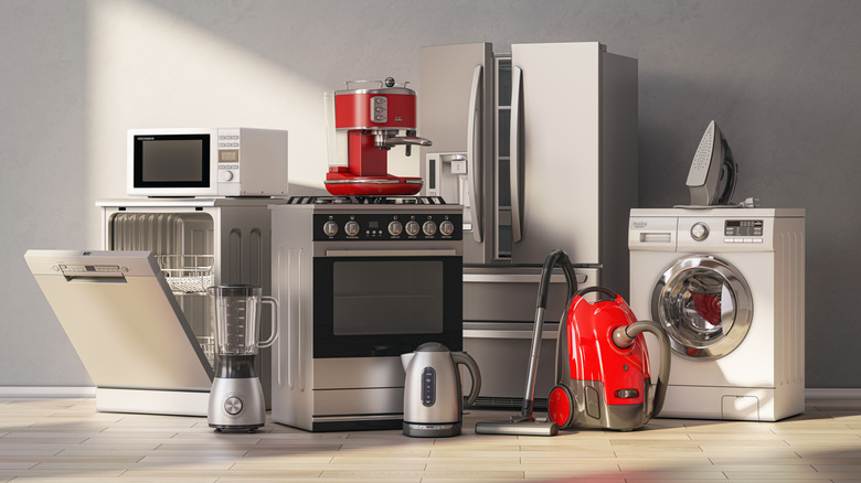 Several kitchen appliances all grouped together, including a blender, a fridge, a vacuum, and an iron.