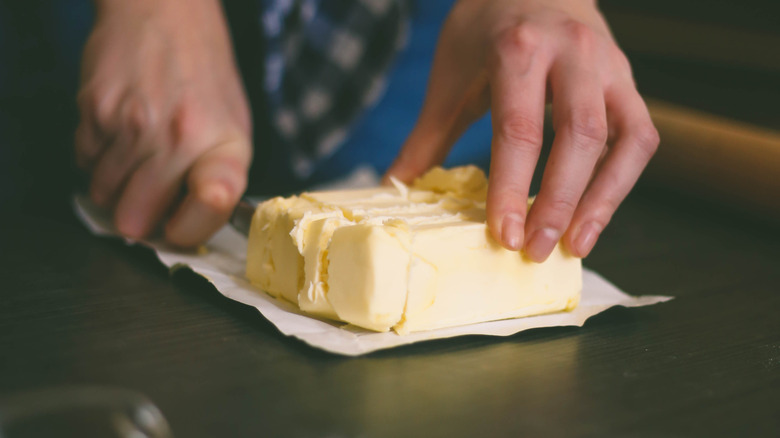A person cuts butter into cubes on a kitchen countertop