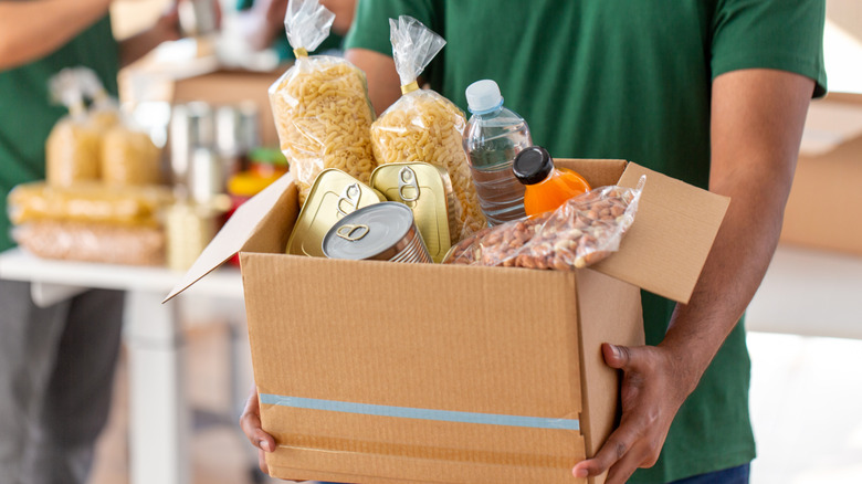 Hands holding cardboard box of food donations