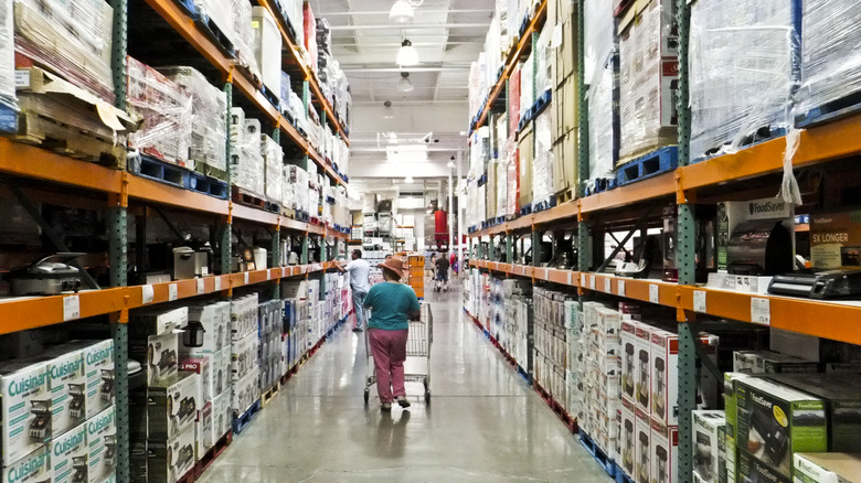 A shopper pushes a shopping cart down an aisle at Costco.