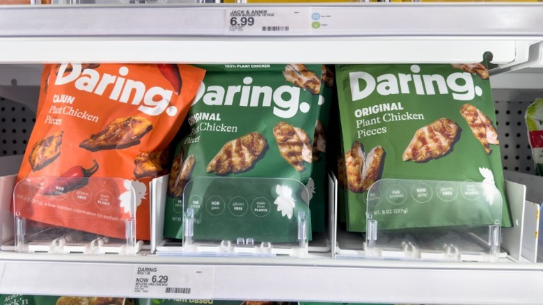 bags of Daring brand Cajun and original plant-based chicken pieces on a grocery store shelf