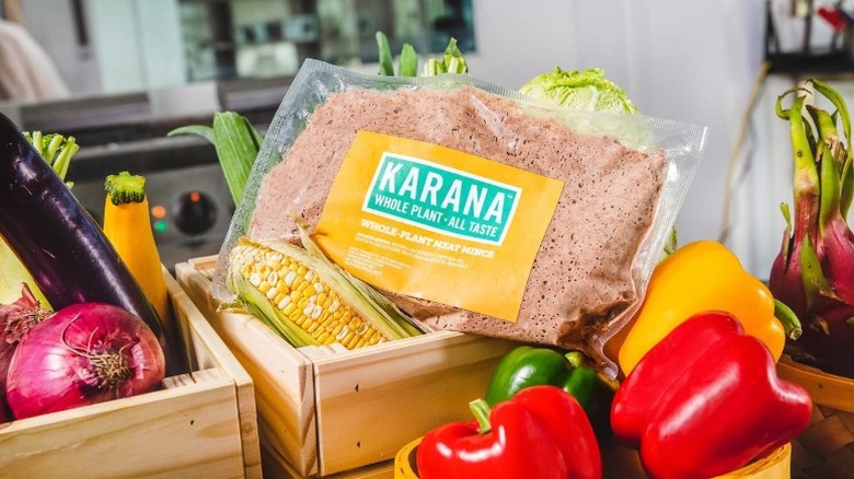 A package of Karana brand jackfruit-based vegan ground meat styled with an array of vegetables in wooden crates