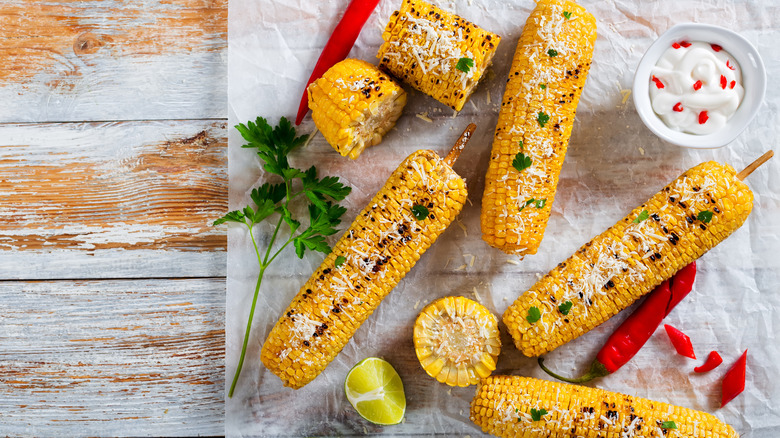 Grilled corn on the cob with fresh red chile pepper, parsley, and grated cheese