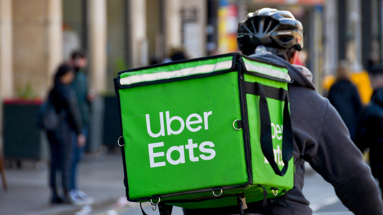 An Uber delivery driver on a bike photographed from behind with a view of their large Uber-branded backpack