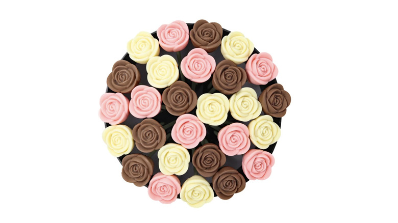 Neatly arranged, modelled chocolate roses in brown, white, and pink seen from above.