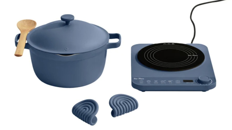 An induction plate, a large pot with a wooden spoon, and two heat pads, all on a white background.