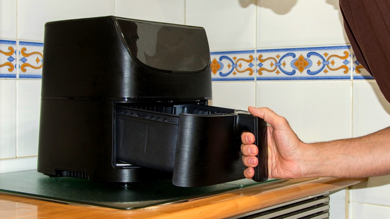 Opening an air fryer basket in a kitchen