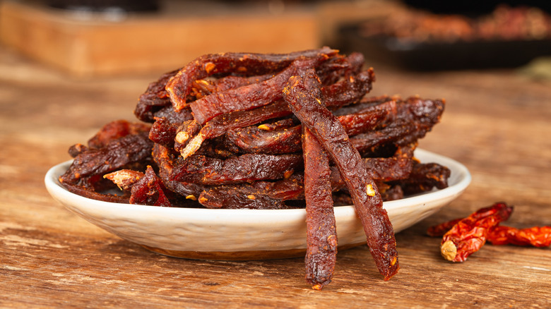 A plate of homemade beef jerky with dried red chiles.