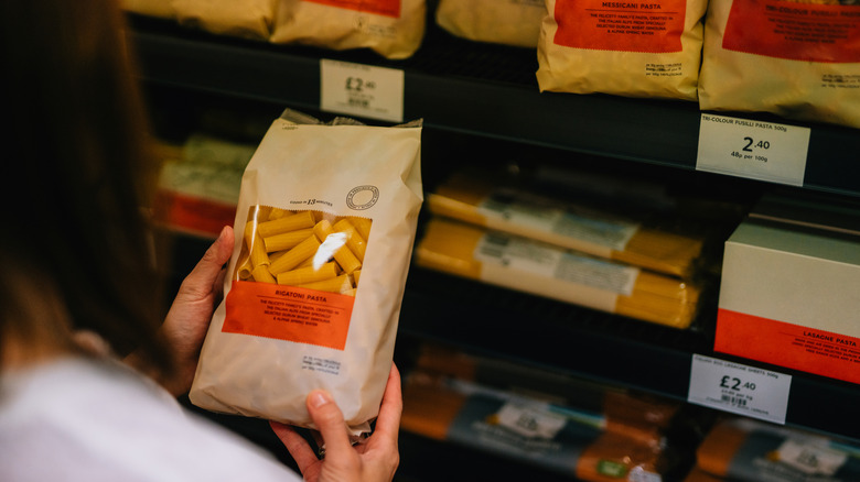 Person holding a bag of dried pasta at the store