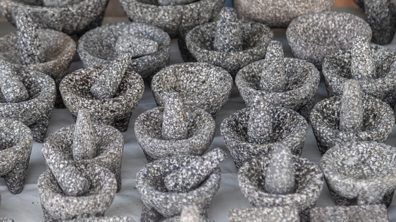 Many handmade molcajetes are lined up on display