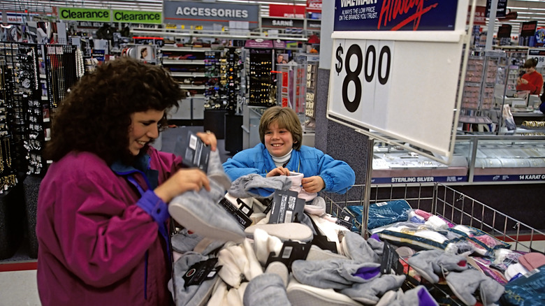 A woman and a child crowding around a bin of merchandise inside an old-school Wal-Mart store