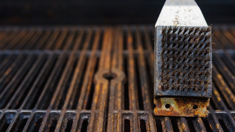 Wire grill brush sitting on top of rusty grill grates