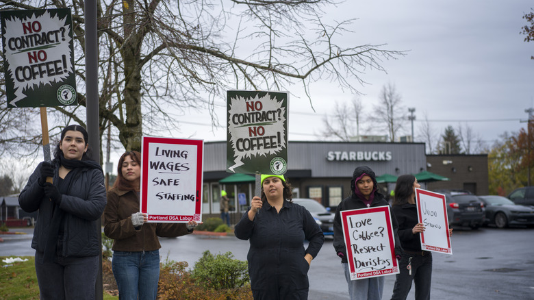 People with signs protest Starbucks labor practices outside a Starbucks store