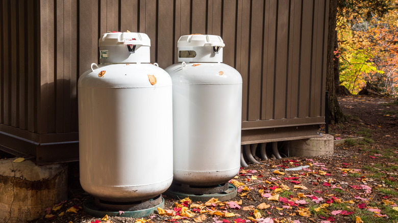 Two large, white propane tanks set against a shed