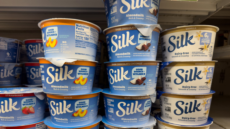 Plant-based yogurt cups from brand "Silk" stacked on top of one another on shelf at grocery store
