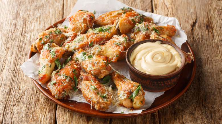 Buttery garlic parmesan chicken wings on a plate with a bowl of mayonnaise