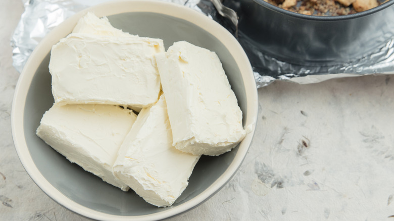 Four blocks of cream cheese in a bowl.
