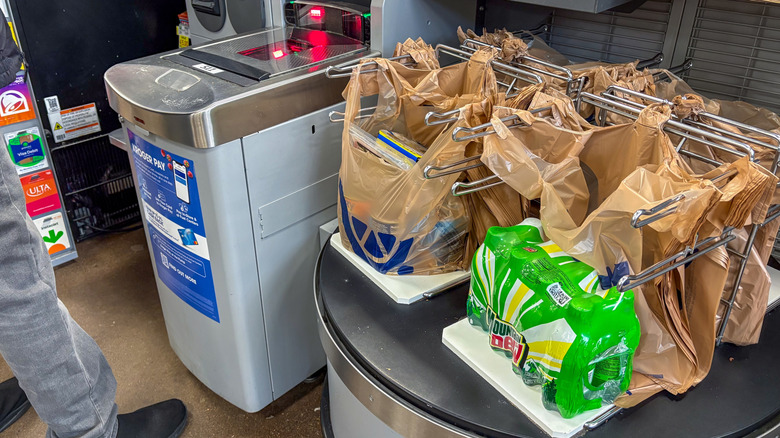 A person at a checkout lane with bags of items at a Kroger
