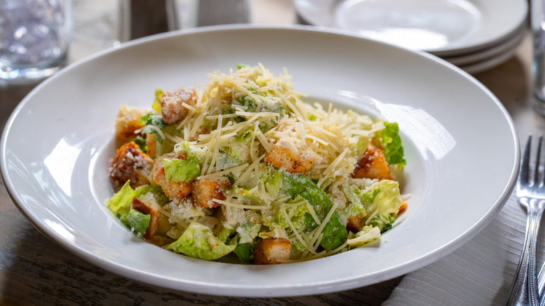 A plate of Caesar salad on an elegantly set table
