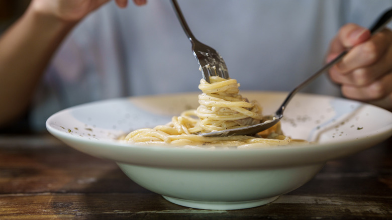 Close-up of an unidentified person eating fettuccine Alfredo