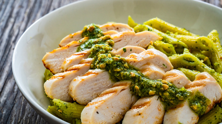 Bowl of grilled chicken on a pesto pasta