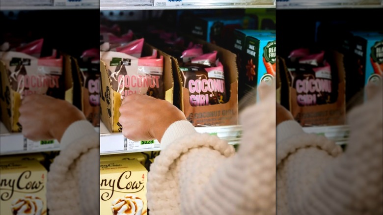 A woman reaches for a Coconut Girl ice cream sandwich in a store freezer