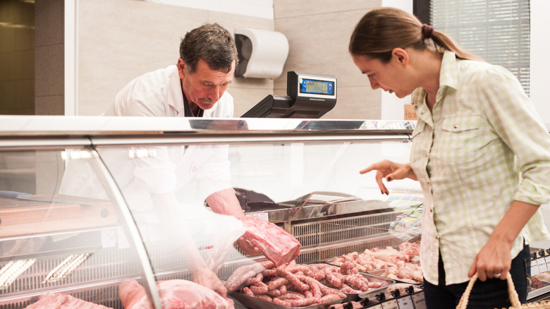 A woman buying meat at the butcher shop.