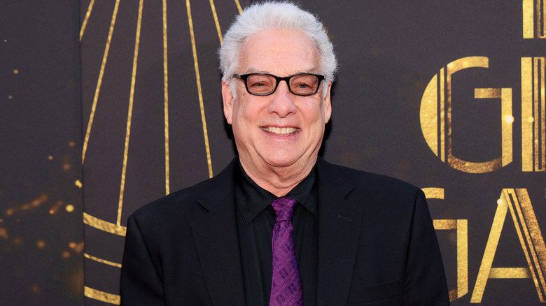 Marc Summers in tinted glasses smiles at an event