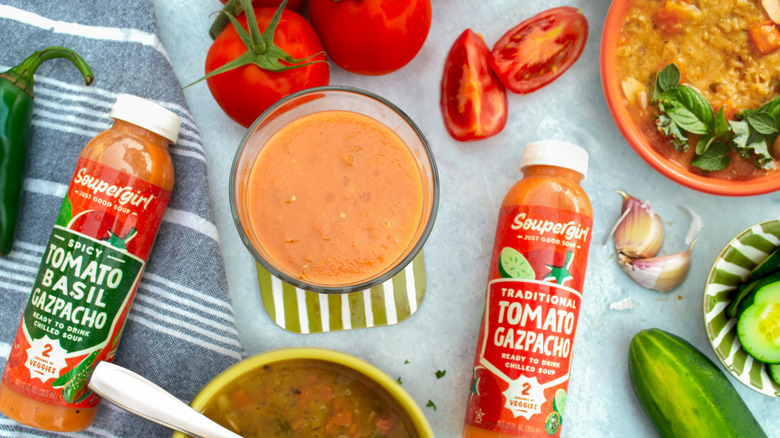 Soupergirl in bottles and served in bowls alongside fresh veggies on a picnic table.