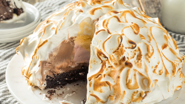 A baked Alaska on a plate with a slice cut out.