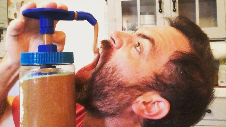Person dispensing peanut butter with the Peanut Butter Pump into their mouth