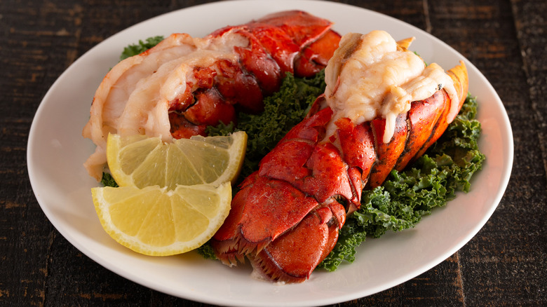 broiled lobster tails with lemon wedges on a white plate
