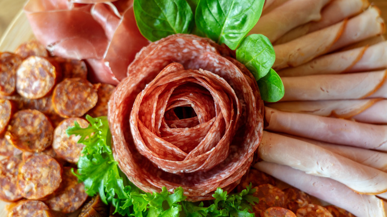 Salami rose surrounded by cured sausage and deli meats