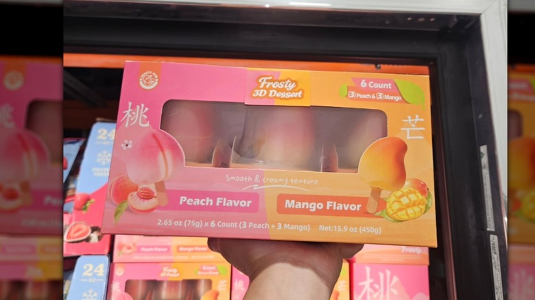 Hand holding up a box of peach and mango ice cream at Costco.