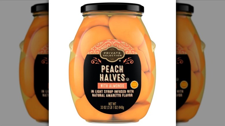 A jar of Private Selection Peach Halves with Almonds on a white background.