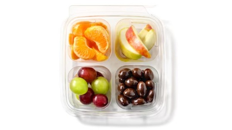 Plastic container filled with oranges, apples, grapes and almonds