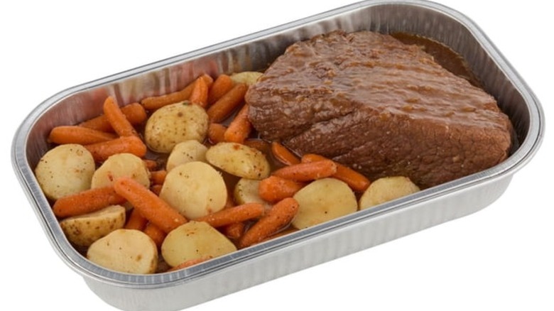 Member's Mark Beef Pot Roast with Carrots and Potatoes in a foil pan on a white background.