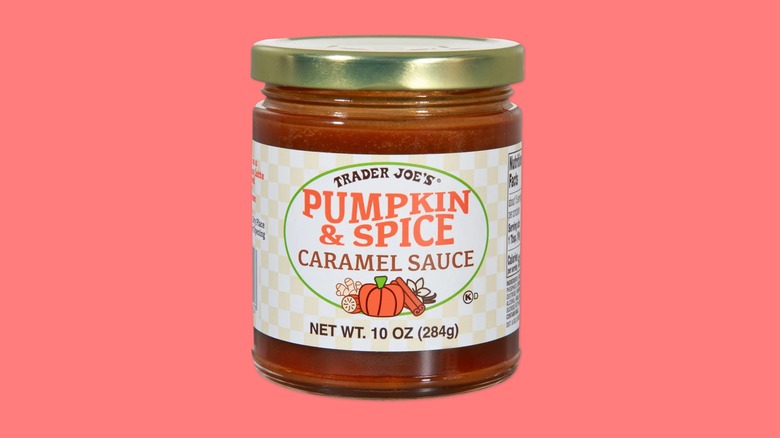 A jar of Pumpkin & Spice Caramel Sauce from Trader Joe's on a pink background.