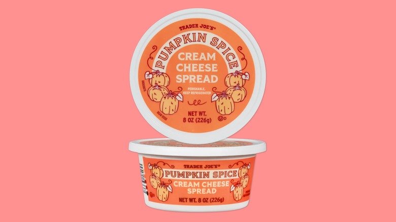 Two containers of Trader Joe's Pumpkin Spice Cream Cheese Spread on a pink background.