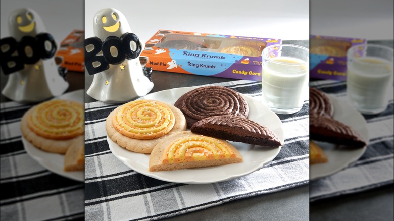 Two King Krumb cookies on a plate with a decorative ghost and a glass of milk.
