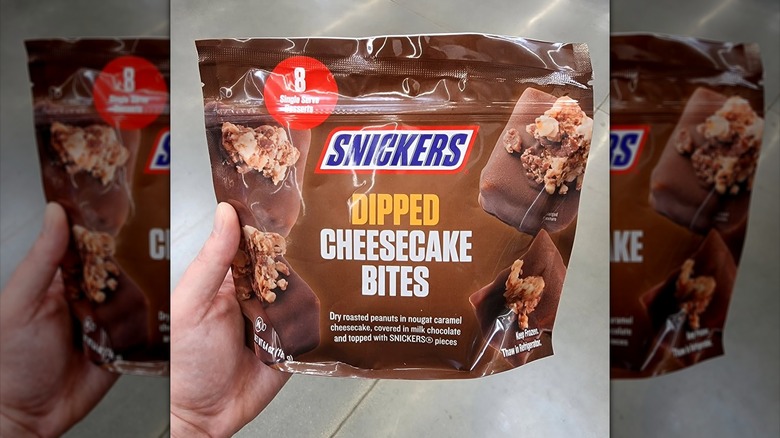 A hand holding the Snickers Cheesecake Bites at Walmart