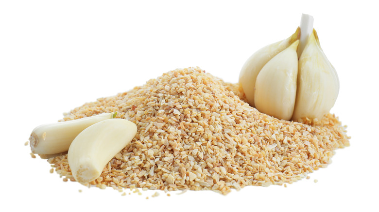 A pile of grabnulated garlic alongside a few whole garlic cloves