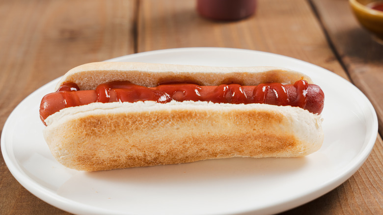 Hot dog with ketchup on white plate