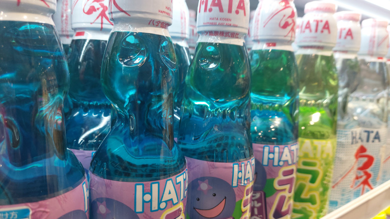 Bottles of ramune sitting on a store shelf.