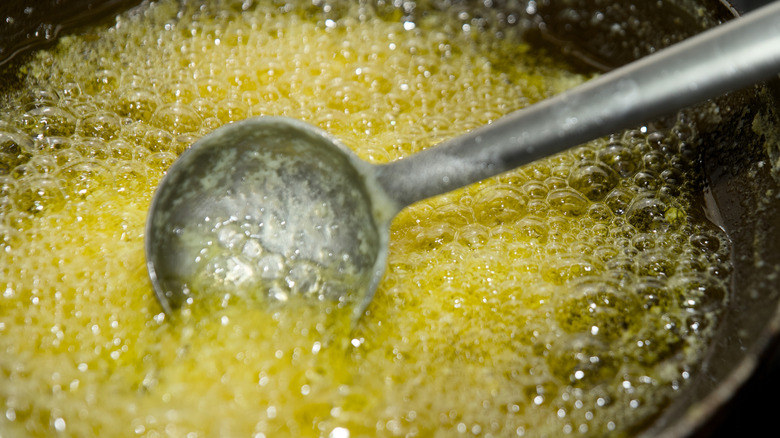 Hot, bubbling ghee with a metal spoon